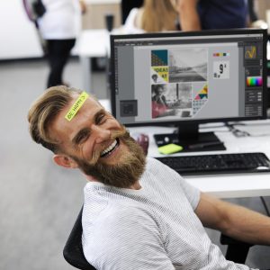man achter computer met post-it be happy op voorhoofd
